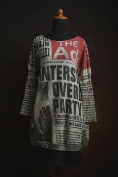Newspaper prints knit sweater dress or tunic with black skirt on a mannequin displayed