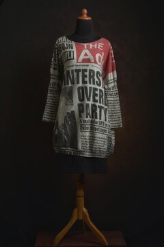 Newspaper prints knit sweater dress or tunic with black skirt on a mannequin displayed