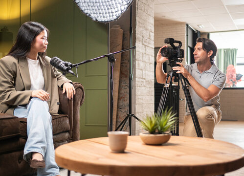 Woman recording a podcast in a studio with a cameraman filming