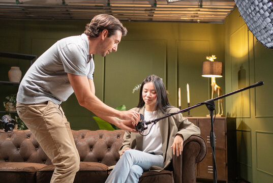 Sound engineer preparing equipment for a young woman recording a podcast or interview