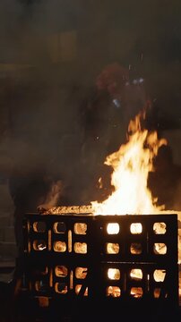 Varanasi, Uttar Pradesh, India. Indian workers man helps a fire burn faster during a funeral cremat