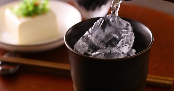 氷の入ったグラスに焼酎を注ぐ