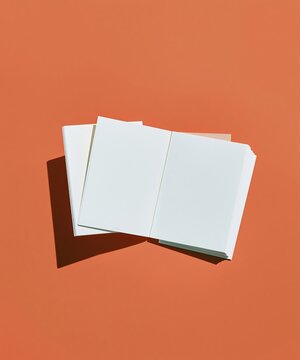 Open blank booklet with plain pages on a warm terracotta orange surface, a clean minimalist mockup with copy space for HR and enrollment layouts