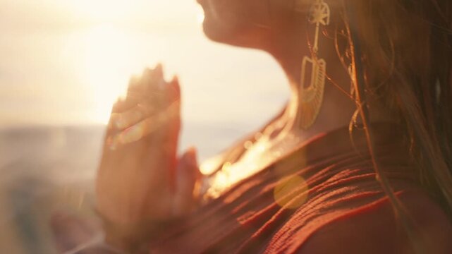 A close up side profile shows praying hands at the water's surface with a dangling gold earring.