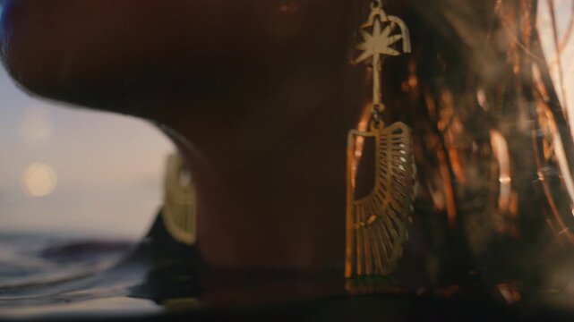 Underwater close up of a wrist wearing a delicate bracelet chain with a dangling charm.
