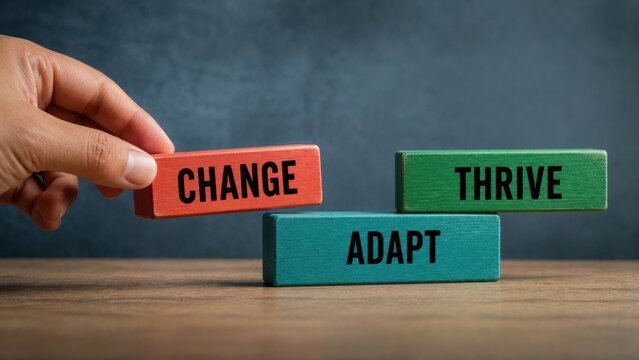 Hand holding red block above green and teal blocks with words change adapt thrive for resilience.