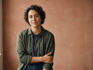 Obraz premium Emotional studio portrait of a non-binary person looking confidently toward the camera, subtle reflective expression, minimalist warm background