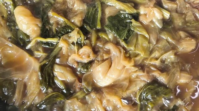Top-down view of traditional Thai-Chinese vegetable stew (Tom Jab Chai) simmering in a large wok. 
