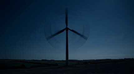 Obraz premium Wind turbine spinning in a dark landscape at twilight for renewable energy
