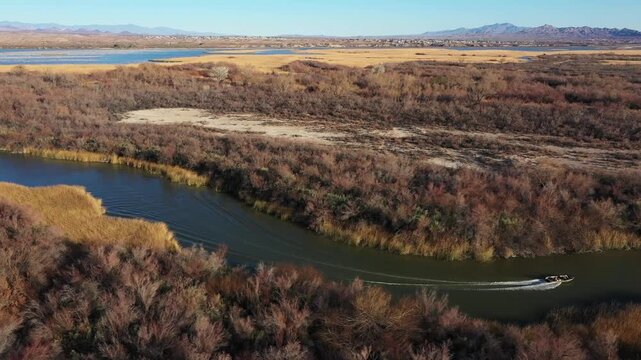 Small motorboat cruising a winding desert river