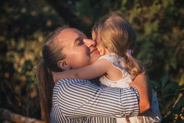 Fototapeta premium A loving mother smiling with her daughter while tenderly hugging.