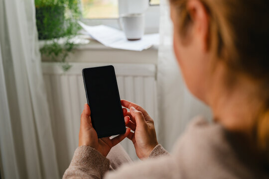 Over the shoulder view of woman using phone at home