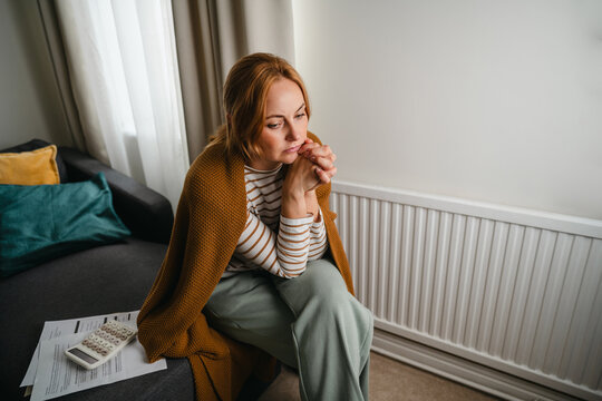 Stressed woman sits alone at home worrying about bills
