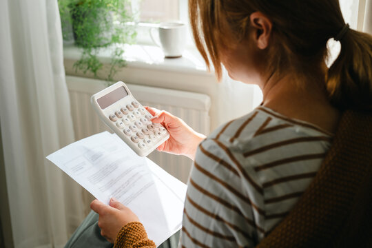 Woman reviewing bills with a calculator at home