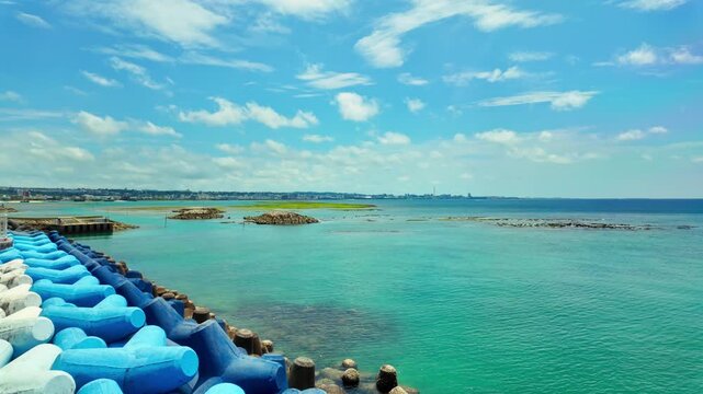 Coastal Breakwater Lined With Blue And White Concrete Tetrapods Along Chatan Park Sunset Beach In Okinawa, Japan. Pan Right Shot