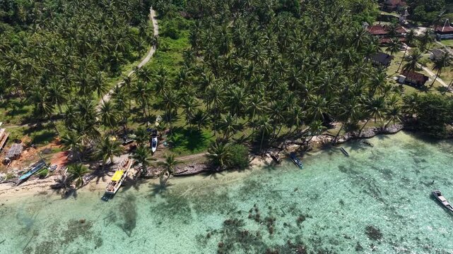 Aerial drone view of Barakuda Beach in Karimunjawa, Indonesia, showcasing white sand, turquoise water, tropical coastline, and lush coconut trees.