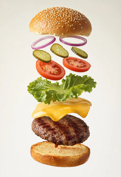 Floating cheeseburger ingredients, deconstructed beef burger layers, flying fast food sandwich