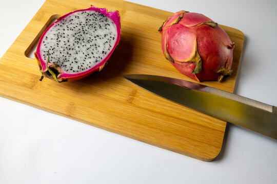 Dragon fruit cut in half on bamboo cutting board