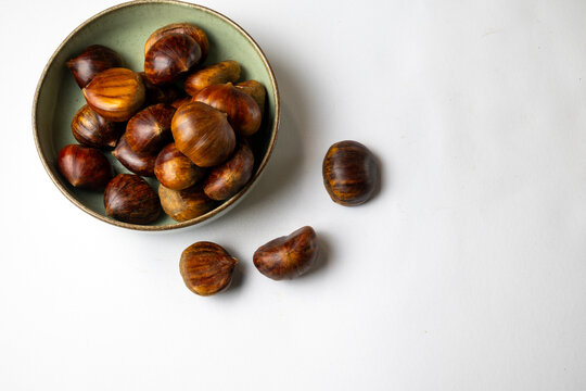 Chestnuts in ceramic bowl on white background