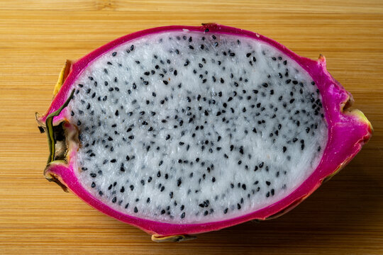 Cut dragon fruit showing white flesh and black seeds