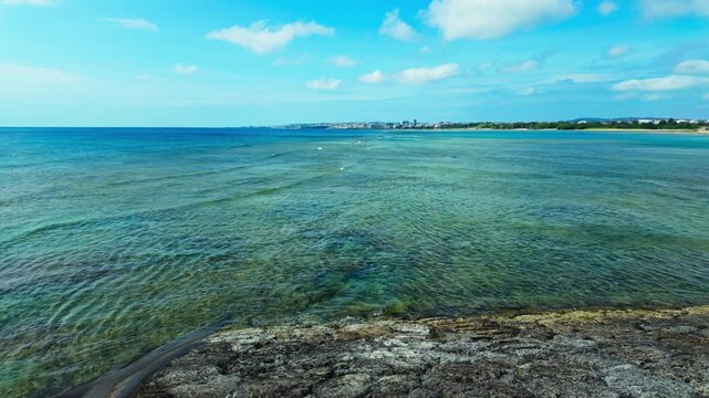 Calm Sea And Coastal Buildings View From The Sunabe Seawall In Chatan, Okinawa, Japan. Pan Right Shot