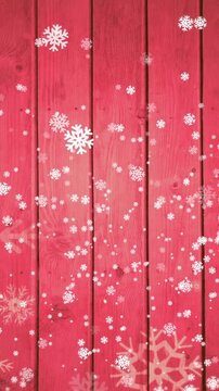 Animation of snow falling on red wooden background with copy space at christmas