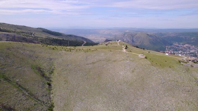 Open rocky plateau above Mostar, Bosnia and Herzegovina with mountain valleys beyond, aerial medium dolly