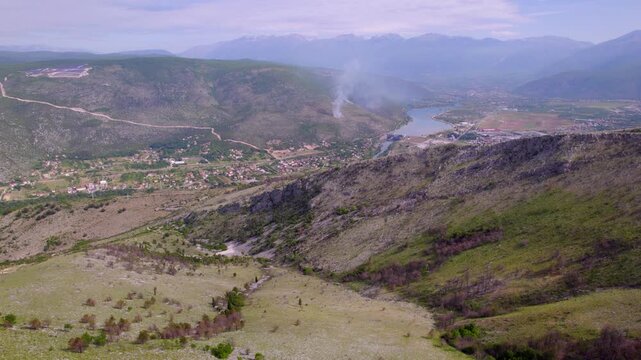 Mountain valley near Mostar, Bosnia and Herzegovina with rocky slopes and distant lake, aerial tracking left