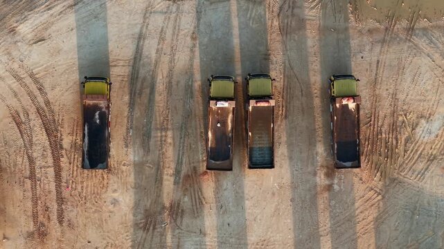 Three keyframes capture an aerial view of five trucks parked on a dirt road