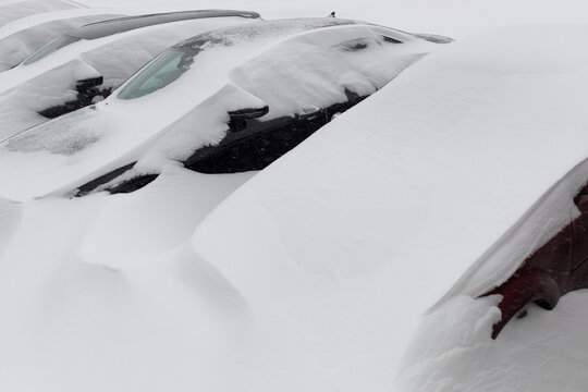 Cars in parking lot are covered with snow after heavy winter snowfall. Natural disasters and climate change.