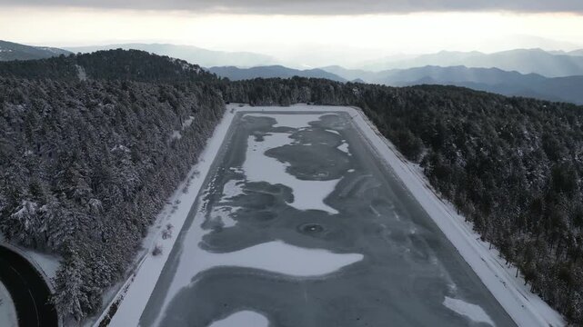 Cinematic drone footage showcasing the frozen waters of Prodromos Dam in winter.