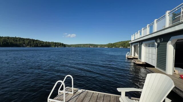Static view across a blue Muskoka lake beside a waterfront boathouse and dock.