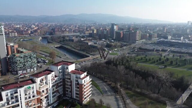 Wide aerial landscape showing Turin urban sprawl, Parco Dora and the immense snowy Alpine range with Monviso, Italy