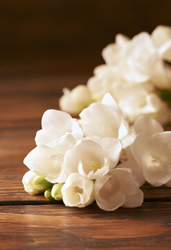 Fresh white freesia blooms on a wooden table, evoking a springtime and natural beauty concept, with a delicate floral composition