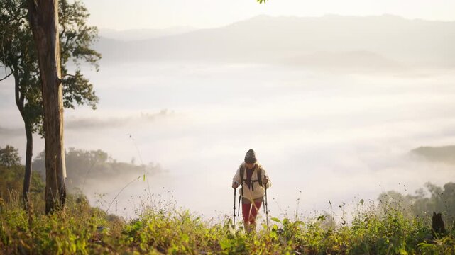 Asian mature woman travel nature hiking on mountain above cloudscape at sunrise. Female traveler with backpack enjoy outdoor adventure, aging gracefully healthy active lifestyle on holiday vacation