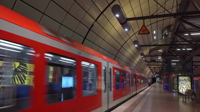 Modern red subway train moving through underground station platform