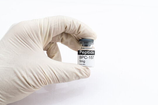 Hand holding BPC 157 peptide vial for research