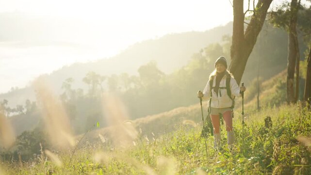 Asian mature woman travel nature hiking on mountain above cloudscape at sunrise. Female traveler with backpack enjoy outdoor active lifestyle , aging gracefully healthy wellness on holiday vacation