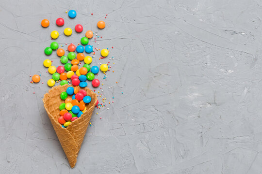 waffle cone full of assorted traditional candies falling out on colored background with copy space. Happy Holidays sale concept