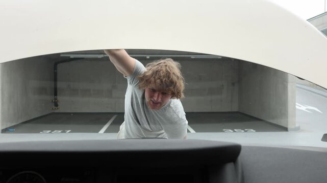 Car owner opens the hood and carefully inspects the engine searching for the cause of an unexpected vehicle breakdown and tries to identify the mechanical problem himself
