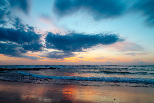 Colorful sunset sky reflecting on wet beach sand