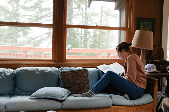 Woman relaxes on a couch reading a book indoors