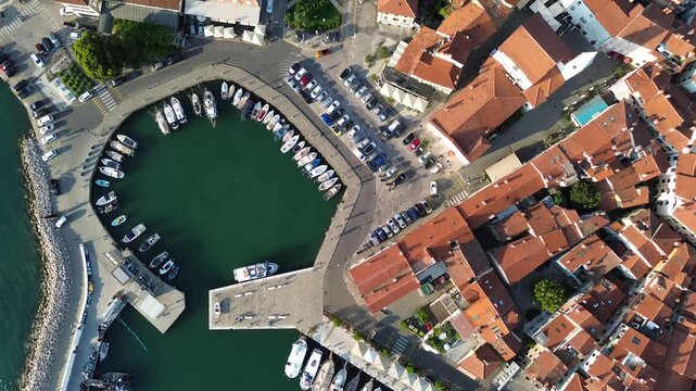 Aerial panorama of Izola, Slovenia, featuring the historic old town, red tiled roofs, marina and beautiful Adriatic coastline on a sunny day.