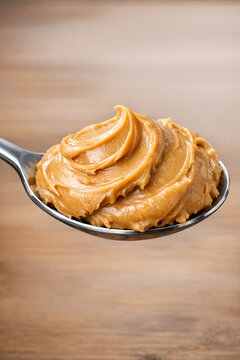 A spoonful of creamy peanut butter on a wooden table.