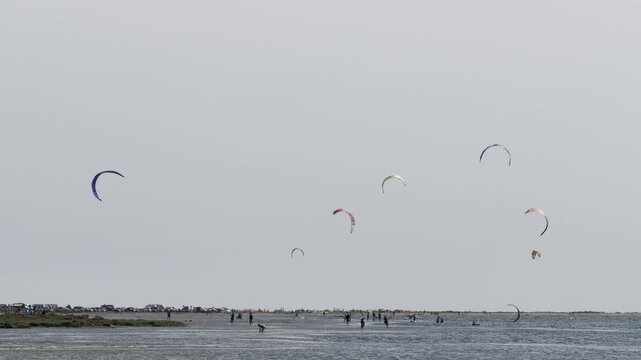 Group of athletes practicing kitesurfing in a beautiful lagoon on a windy summer day
