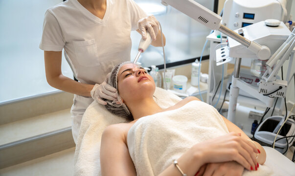 Full length wide shot of woman having darsonval electrotherapy procedure in salon