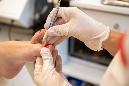 Close up of professional manicurist using cuticle pusher tool during pedicure