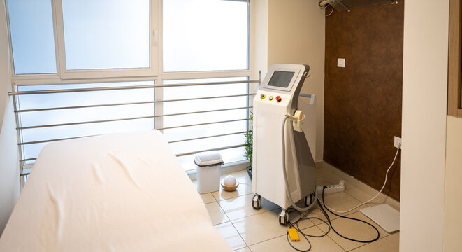 Empty modern cosmetology room with laser hair removal machine and bed