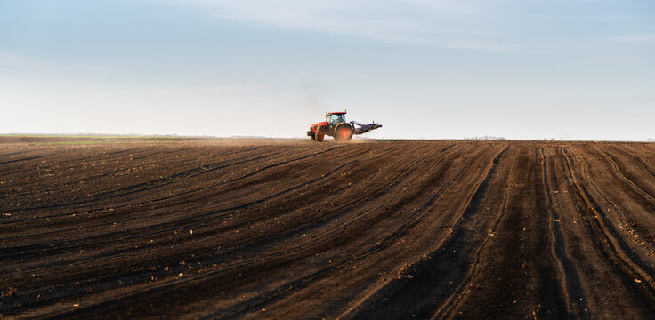 Modern tractor working cultivated soil in rural farmland