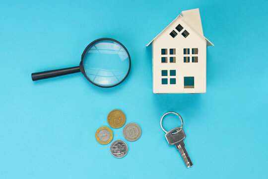 High Angle of Miniature Model Beside Magnifying Glass and Metal Key Over Blue Background